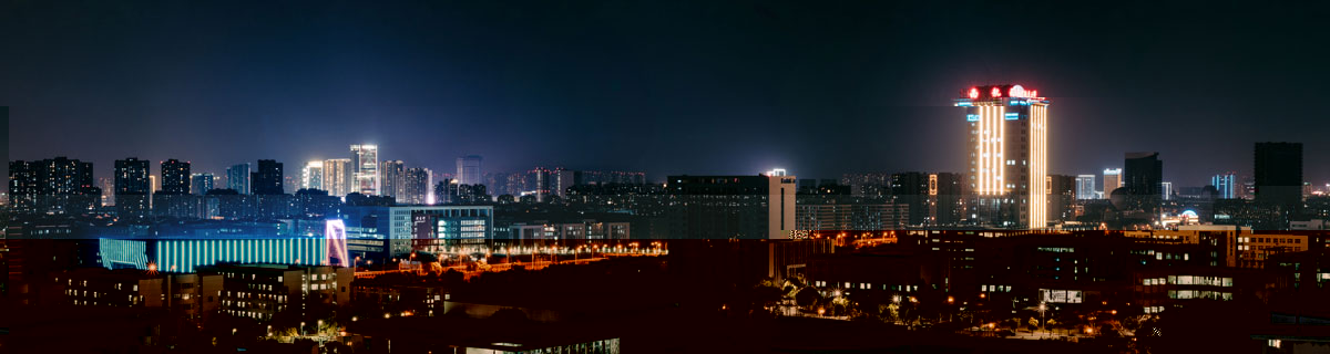 Nighttime city skyline with illuminated skyscrapers and streets, dark blue and warm light tones, urban and vibrant mood.